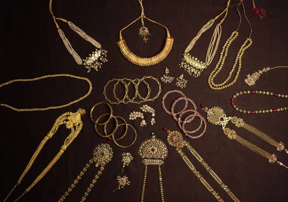 Traditional Indian gold necklaces, bangles and earrings laid out on a dark cloth