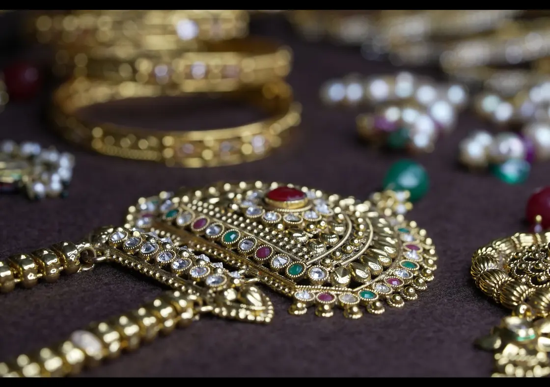 Close-up of traditional Indian gold jewellery: bangles and a stone-set pendant