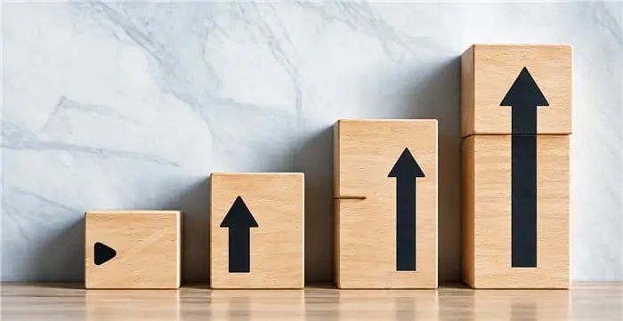 Wooden blocks with upward arrows in ascending steps, symbolising business growth