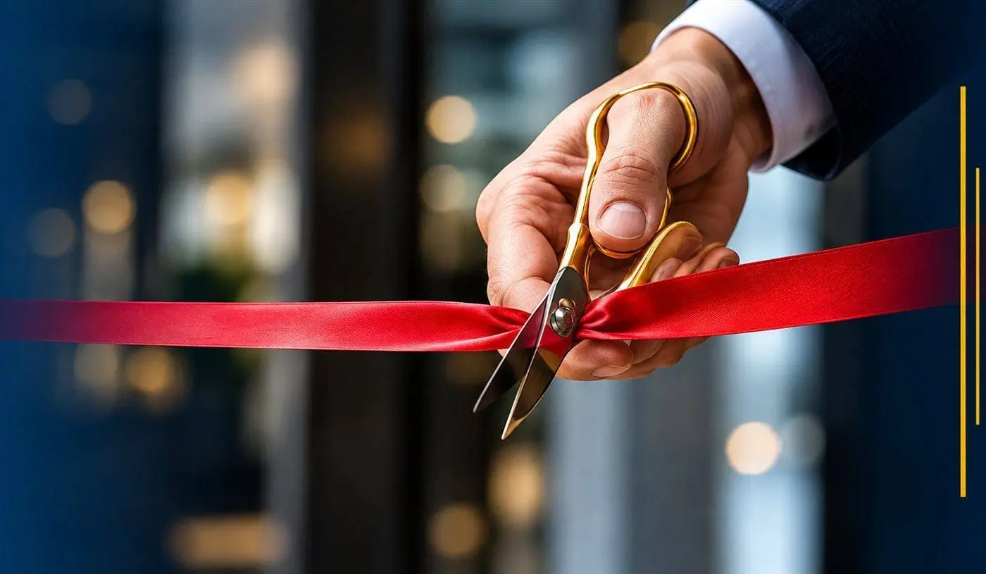 Hand cutting a red ribbon with gold scissors at a store opening